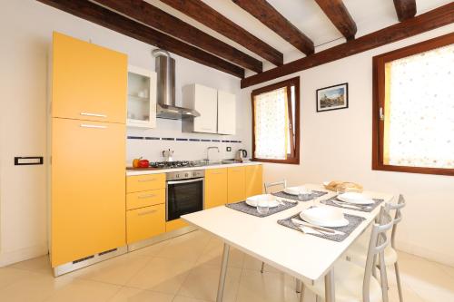 a kitchen with a white table and yellow cabinets at Bricola Biennale Apartments in Venice