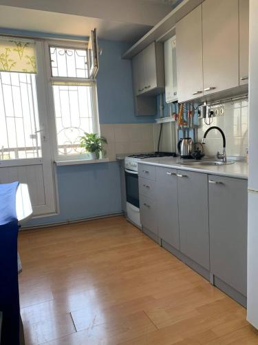 a kitchen with white cabinets and a wooden floor at КВАРТИРА с видом на площадь in Shymkent