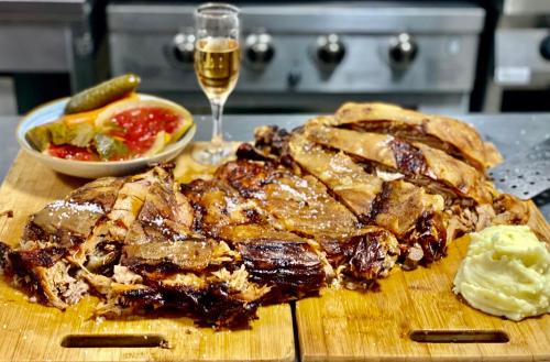 a wooden cutting board with meat and a glass of wine at Pensiunea Știuca Șchioapă in Băltenii de Sus