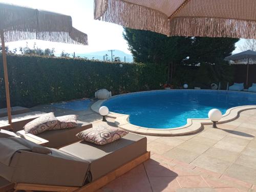 a swimming pool with a couch and an umbrella at Luxury Villas Chrysa Private Pool & Spa in Nafplio
