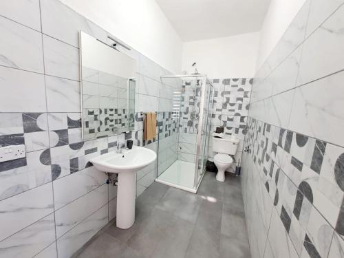 La salle de bains blanche est pourvue d'un lavabo et de toilettes. dans l'établissement Rotas B, à San Ġiljan