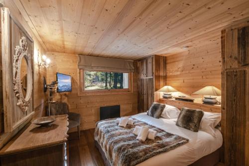 una camera da letto in una baita di tronchi con letto e scrivania di Chalet Peyrlaz a Chamonix-Mont-Blanc