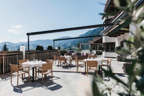 a patio with tables and chairs with mountains in the background at Sonnhof Alpendorf - an adults only place in Sankt Johann im Pongau