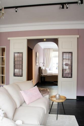 een woonkamer met een witte bank en een slaapkamer bij Suite 137, luxe verblijf midden in de bollenstreek in Lisse