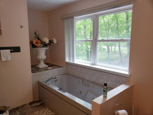 uma banheira na casa de banho com uma janela em Fantastic Poconos home w/ Fireplace + More!!! em Long Pond