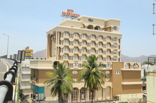 a hotel with palm trees in front of a building at HOTEL SALEM CASTLE in Salem