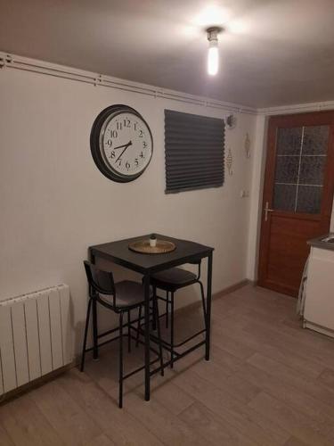 a table and chairs in a room with a clock on the wall at Petit maison villageoise in Moulineaux