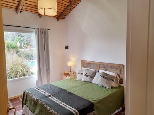 a bedroom with a green bed with a window at Complejo Dulcería El Cazador y cabañas in Tandil