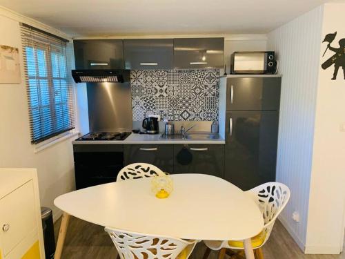 une petite cuisine avec une table et des chaises blanches dans l'établissement Appart cocooning avec parking gratuit & wifi, à Le Touquet-Paris-Plage