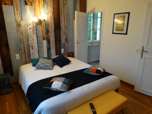una camera da letto con un letto con cuscini sopra di Le Cèdre Bleu - Maison d'hôtes 