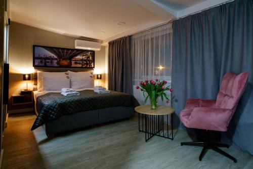 une chambre d'hôtel avec un lit et une chaise rose dans l'établissement Kamienica no 111a, à Varsovie