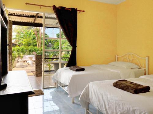 a room with three beds and a window with a patio at Blue Beach Resort in Baanphakrimlay 