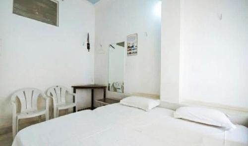 a white bedroom with a bed and a table and chairs at Lalghat Haveli in Udaipur