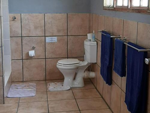a bathroom with a toilet and blue towels at Venha Juntos Guest Homes in Miramar