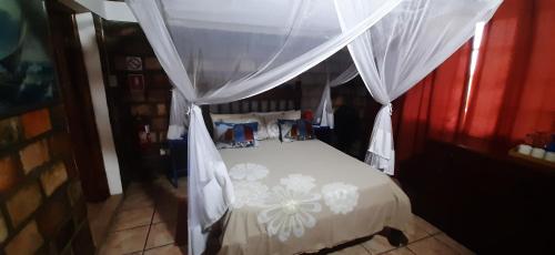 a bedroom with a white bed with a canopy at Venha Juntos Guest Homes in Miramar