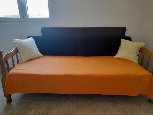 ein orangefarbenes Bett mit zwei Kissen in einem Zimmer in der Unterkunft Gospava Apartman in Igalo