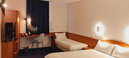 a hotel room with two beds and a desk and a chair at Deltour Hôtel - L'Adresse Ruthénoise in Rodez