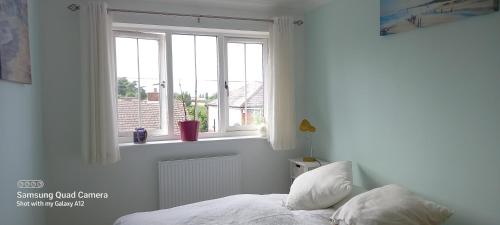 a white bedroom with a bed and a window at 2 Orchard Gate in Kent
