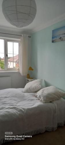 a white bed with two pillows and a window at 2 Orchard Gate in Kent