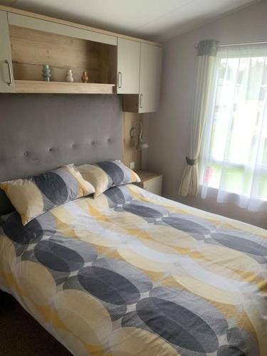 a bedroom with a bed with a comforter and a window at Grasmere Lodge Unit 31 in Carlisle