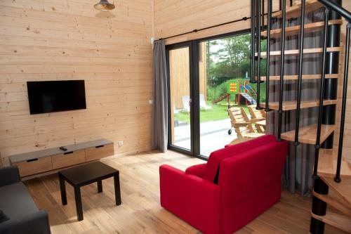 salon z czerwoną kanapą i telewizorem w obiekcie Kapitanka Apartamenty w Okunince