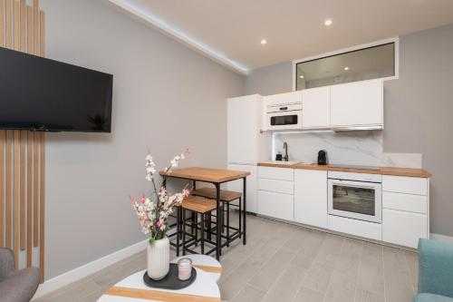 - une cuisine avec des placards blancs et une table fleurie dans l'établissement Modern Apartment - Promenade des Anglais in Nice, à Nice