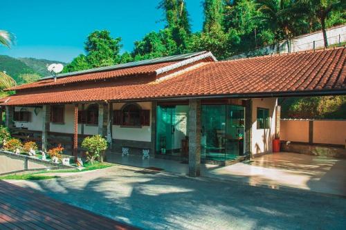 a house with a tiled roof and a patio at Chácara Alegria - Um pedaço do paraíso em Itaboraí in Itaboraí