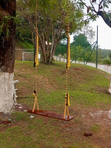 a swing in a park next to a tree at Chácara Alegria - Um pedaço do paraíso em Itaboraí in Itaboraí