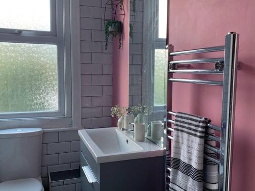 a bathroom with a sink and a pink wall at Margate Escape House, sleeps 5-6. Free parking. in Kent