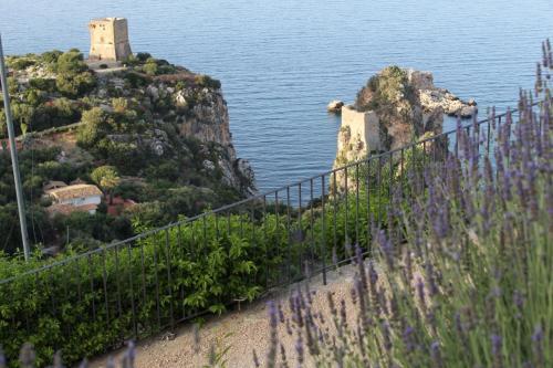 uma vista para uma ilha na água com flores roxas em CasAnna em Castellammare del Golfo