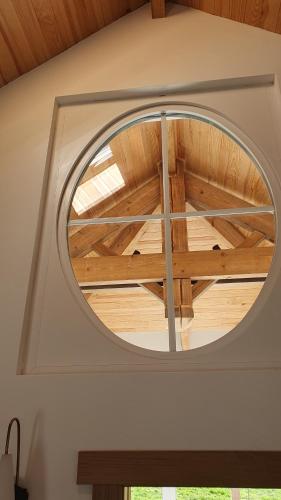 a round window in a room with a wooden ceiling at Le gîte de la ChèBrerie in Forrières