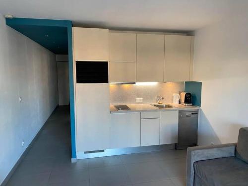 a kitchen with white cabinets and a sink and a couch at Charmant appartement à Port Grimaud in Grimaud
