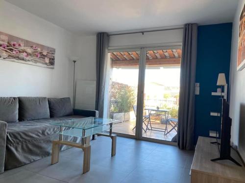 a living room with a couch and a glass table at Charmant appartement à Port Grimaud in Grimaud