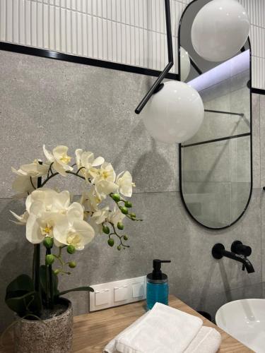 łazienka z umywalką i wazą z białymi kwiatami w obiekcie Apartamentowiec Opole w mieście Opole