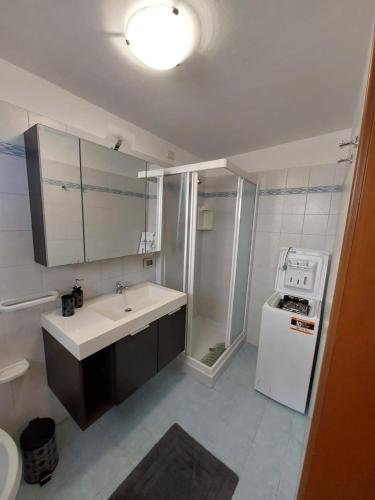 une salle de bain avec un lavabo et une machine à laver dans l'établissement Appartamento al faro, à Caorle