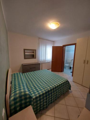 - une chambre avec un lit et une couverture verte en damier dans l'établissement Appartamento al faro, à Caorle