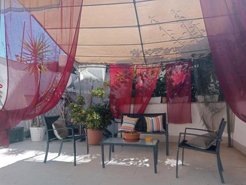 un patio con mesa, sillas y cortinas en Dietro il massimo, en Palermo