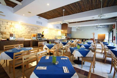 a dining room with blue tables and wooden chairs at Hotel Mariachi by Kavia 5th Av in Playa del Carmen