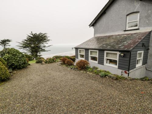 a house with a gravel driveway in front of it at Sibrwd Y Mor in Harlech