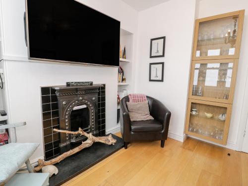 a living room with a fireplace and a television on a wall at Sibrwd Y Mor in Harlech