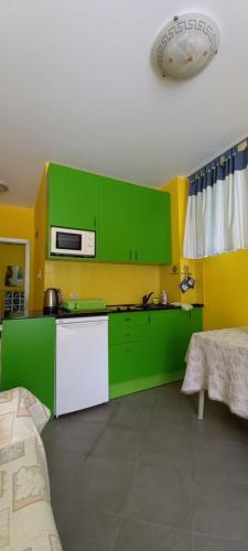 een keuken met groene kasten en een witte koelkast bij Уютные 2-х комнатные апартаменты in Pomorie