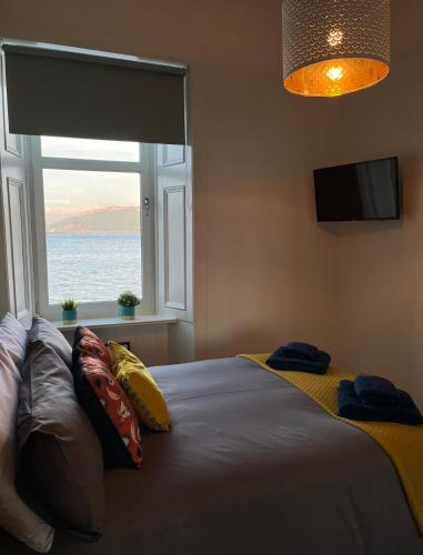 a bedroom with a bed with a large window at Beautiful Upper Apartment/Stunning Sea Views, Isle of Bute in Port Bannatyne