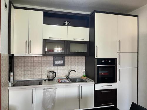 una cocina con armarios blancos y fregadero en Apartment Idea en Novi Pazar