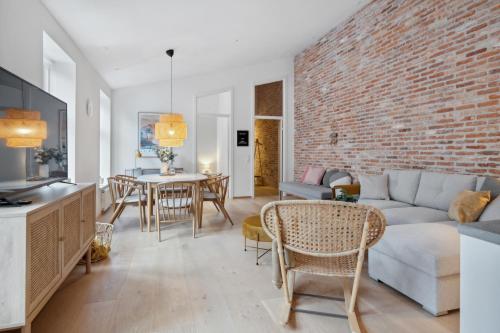 a living room with a couch and a brick wall at Central 3-bedroom apartment with huge terrace, including queen size beds in Aalborg