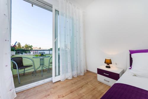 a bedroom with a bed and a balcony with a table at Apartment Sara in Zadar