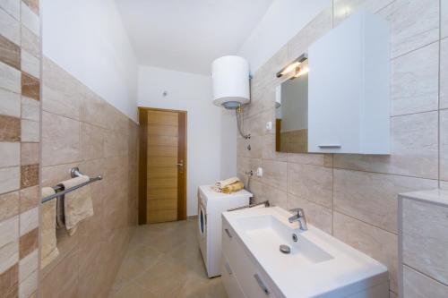 a white bathroom with a sink and a mirror at Apartment Sara in Zadar
