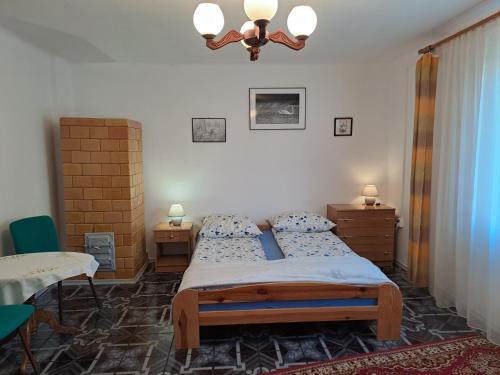 a bedroom with a bed and a table and a chandelier at Domek u Jadzi in Zwierzyniec