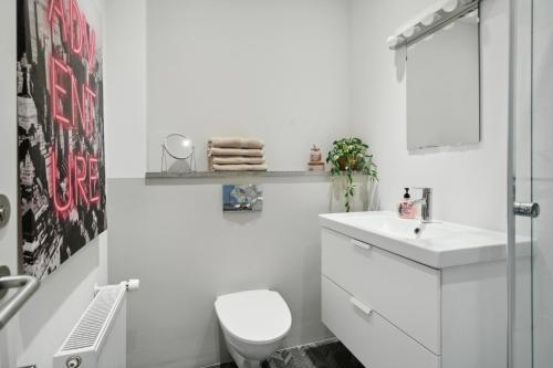 a white bathroom with a toilet and a sink at Central 3-bedroom apartment with a big terrace and fitness room in Aalborg