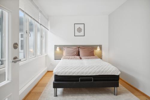 ein Schlafzimmer mit einem Bett in einem weißen Zimmer mit Fenstern in der Unterkunft Central 3-bedroom apartment with a big terrace and fitness room in Aalborg