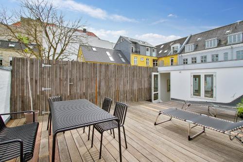 a wooden deck with chairs and a table and a fence at Central 3-bedroom apartment with huge terrace, including queen size beds in Aalborg